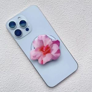 Close-up of a pink orchid acrylic magnetic phone holder on a blue smartphone