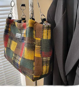 Detail of multi-color plaid tote bag with black leather handle and chain strap