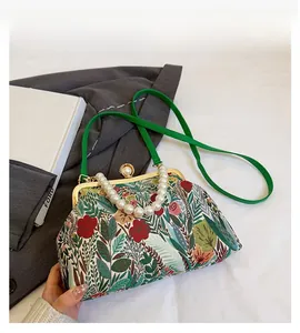 Detail of floral fabric crossbody bag featuring a pearl handle and metal clasp closure