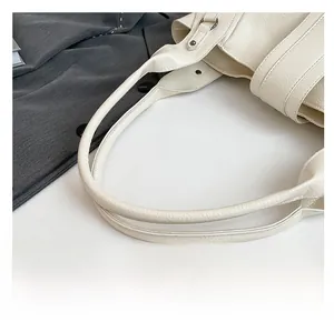 Détail de la bandoulière renforcée et boucle en métal sur ce sac cabas crème