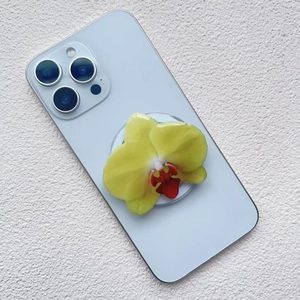 Macro shot of 3D yellow orchid phone grip mounted on a light blue smartphone back