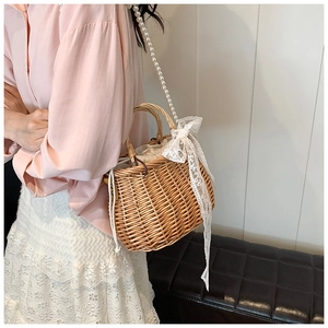Detail of straw woven bag featuring pearl strap, lace bow, and drawstring lining