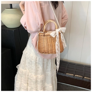 Detail of straw woven bag with white lace bow and elegant pearl chain shoulder strap