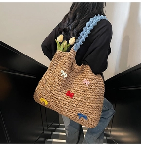 Detail of handmade straw tote bag featuring colorful bows and blue fuzzy shoulder strap