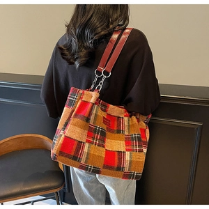 Detail of tartan woven tote bag featuring red patent leather and metal chain shoulder strap