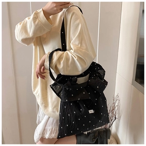 Close-up of black floral tote bag showing delicate white flower patterns and fabric texture