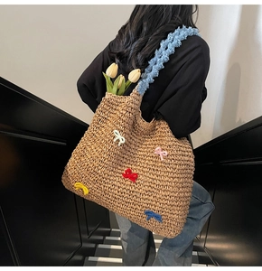 Detail of straw tote bag with colorful 3D bows and blue ruffled shoulder straps