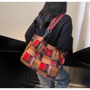 Detail of red and brown plaid tote bag with leather strap and metallic chain link