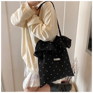 Detailed close-up of a black floral tote bag with Magic pocket label and white flowers