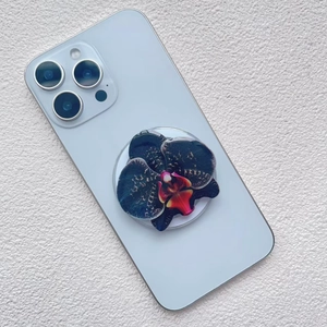 Close-up of a dark purple orchid magnetic phone grip on a grey smartphone back