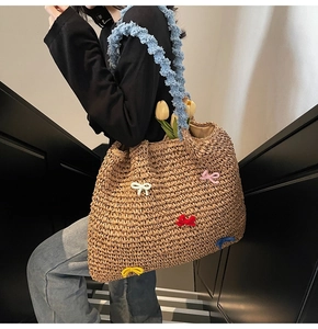 Detail of straw woven tote bag featuring colorful 3D bows and blue ruffled shoulder strap