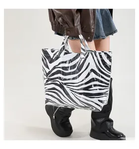 Détail d'un sac cabas imprimé zèbre avec texte blanc porté par un mannequin stylé