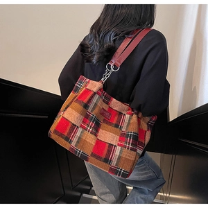 Detail of red and brown plaid tote bag with stylish metal chain and leather shoulder strap