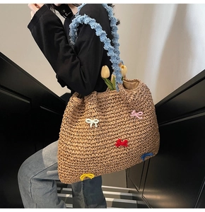 Detail of straw woven tote bag featuring colorful 3D bows and blue fuzzy handles
