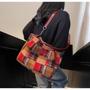 Detail of tartan tote bag with red leather strap and metallic chain connectors