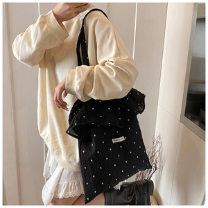 Detail of black floral tote bag with large ruffle trim and Magic pocket woven label