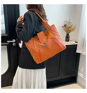 Gros plan d'un grand sac cabas orange en similicuir grainé avec pendentif en métal et zips