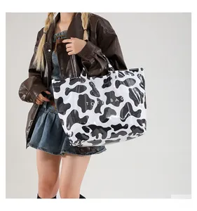 Grand sac cabas étanche à motif vache avec finition brillante porté par un mannequin