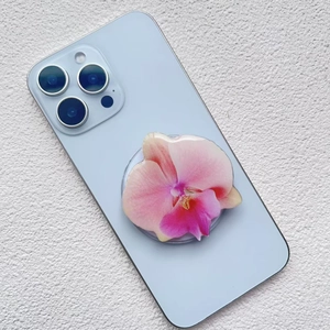 Pink orchid flower magnetic phone grip with semi-transparent petals on a blue smartphone