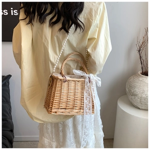 Detail of straw woven bag with white lace bow, pearl strap, and drawstring liner