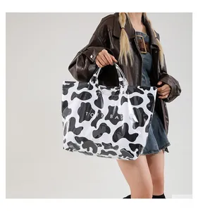 Sac fourre-tout brillant à motif vache noir et blanc avec texte blanc sur le mannequin