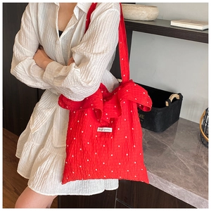 Detail of red floral tote bag with Magic Pocket label and elegant ruffled edge design