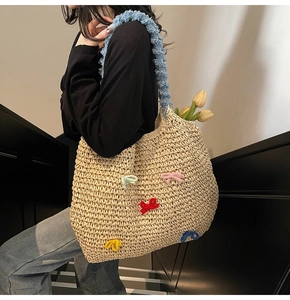 Close-up of handmade straw tote featuring colorful crochet bows and blue plush shoulder strap