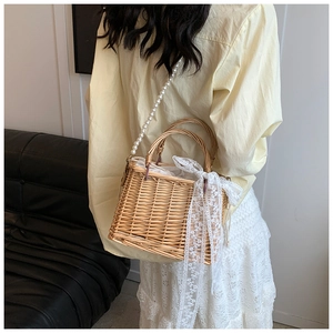 Detail of straw basket bag featuring pearl strap and long white lace ribbon decoration