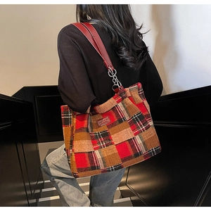 Detail of red checked tweed tote bag with leather strap and chain worn by a model