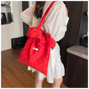 Detail of red floral tote bag with textured fabric and large side bow decoration