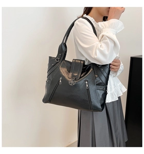Gros plan du sac cabas noir avec boucles florales argentées et détails zippés latéraux