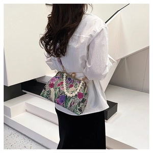 Detail of vintage floral jacquard handbag featuring a luxury faux pearl handle and metal clasp