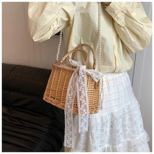 Detailed close-up of handmade straw bag with large lace bow and pearl crossbody strap