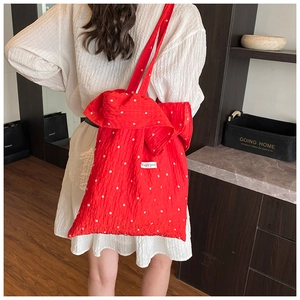 Detail of red floral chiffon shoulder bag with large bow and ruffled texture fabric