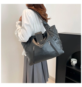 Détail du cabas noir avec fermoir floral argenté et poches latérales zippées