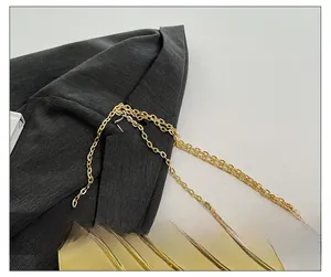 Dettaglio della borsa box in acrilico oro lucido con strisce verticali e catena metallo