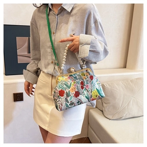 Detailed view of vintage floral crossbody bag with pearl handle and metal clasp closure