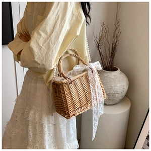 Detail of woven straw basket bag with pearl strap and white lace bow decoration