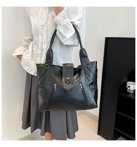 Détail du grand sac cabas noir avec emblème floral en métal et poches zippées latérales
