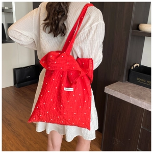 Detailed view of a red floral tote bag with Magic Pocket label worn on a white dress