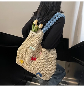 Detail of straw woven tote with colorful yarn bows and blue plush shoulder strap
