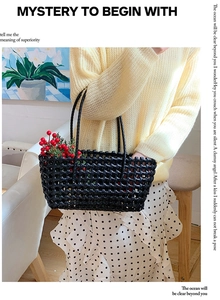 Detail of a black woven tote bag featuring an intricate hollow grid mesh design and pattern
