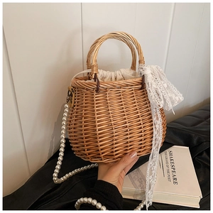 Detail of straw woven handbag featuring lace bow, pearl strap, and drawstring liner
