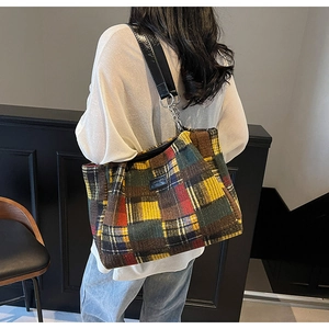 Detailed shot of multi-color plaid tweed tote bag with metal chain strap and leather patch