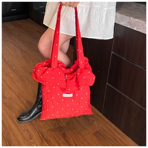 Detail of red floral puffer tote bag with 'Magic Pocket' label and puffy texture