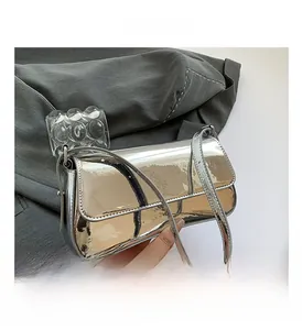 Detailed view of silver patent leather baguette bag resting on a tailored grey suit jacket