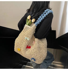 Detail of straw woven tote bag featuring colorful 3D bows and soft blue plush handles
