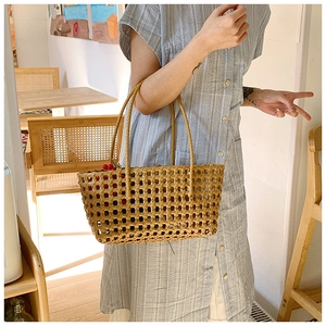 Detail of hollow woven tote bag with diamond mesh pattern and cherry decor on shirt dress