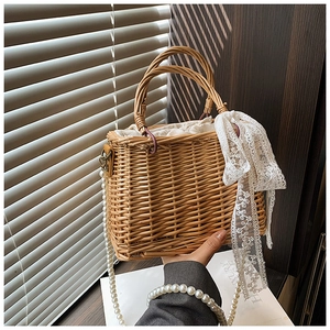 Detail of straw woven shoulder bag with pearl strap and white lace ribbon decoration