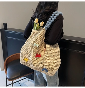 Detail of handwoven straw tote bag with colorful bows and blue plush shoulder strap